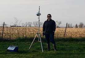 Rachel Marek stands next to a collection instrument outdoors