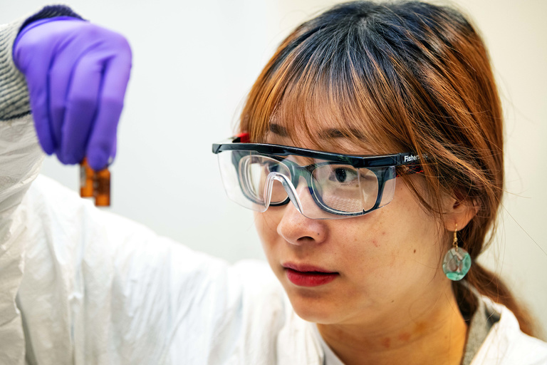 A researcher examining vials